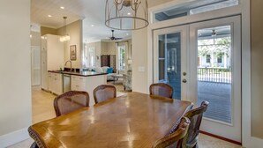 A dining area with a wooden table and chairs, a chandelier, and a view of the outside through a sliding glass door. - 1016 San Fernando Street 3 Bedroom Home by RedAwning (Fernandina Beach)