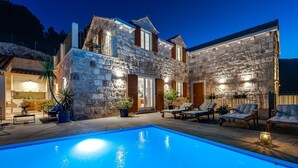 Une maison en pierre dotée d’une piscine, d’un espace extérieur aménagé pour s’asseoir et d’un patio bien éclairé.