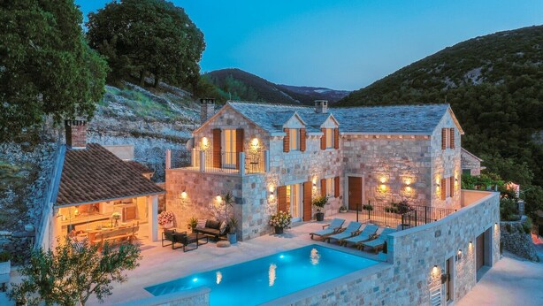 Une villa en pierre dotée d’une piscine, d’un espace extérieur aménagé et d’un bar.