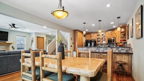 Una cocina moderna con armarios de madera, una mesa de comedor y taburetes de bar.