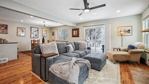 Una sala moderna con un sofá modular, una chaise longue y un comedor con mesa y sillas.