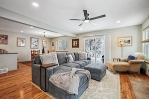 A modern living room with a sectional sofa, a chaise lounge, and a dining area with a table and chairs.