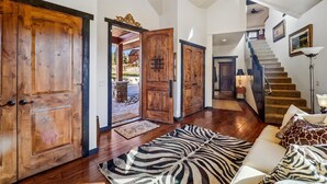 Un hall d’entrée spacieux doté d’un plancher en bois, d’un tapis à motifs zébrés et d’un escalier menant à l’étage supérieur.