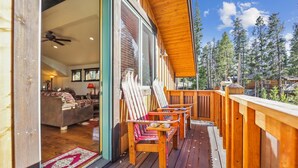 Une terrasse en bois avec des sièges extérieurs et une vue sur une forêt.