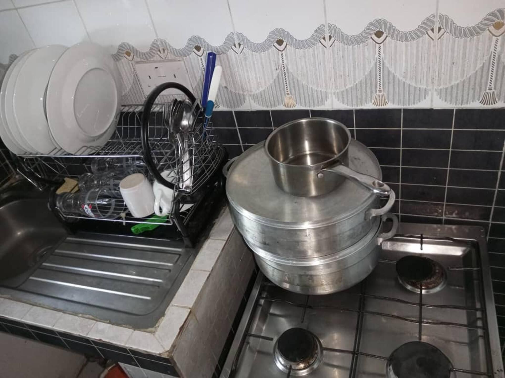 Una cocina con estufa, pileta y escurridor.