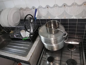 A kitchen with a stove, sink, and dish rack.