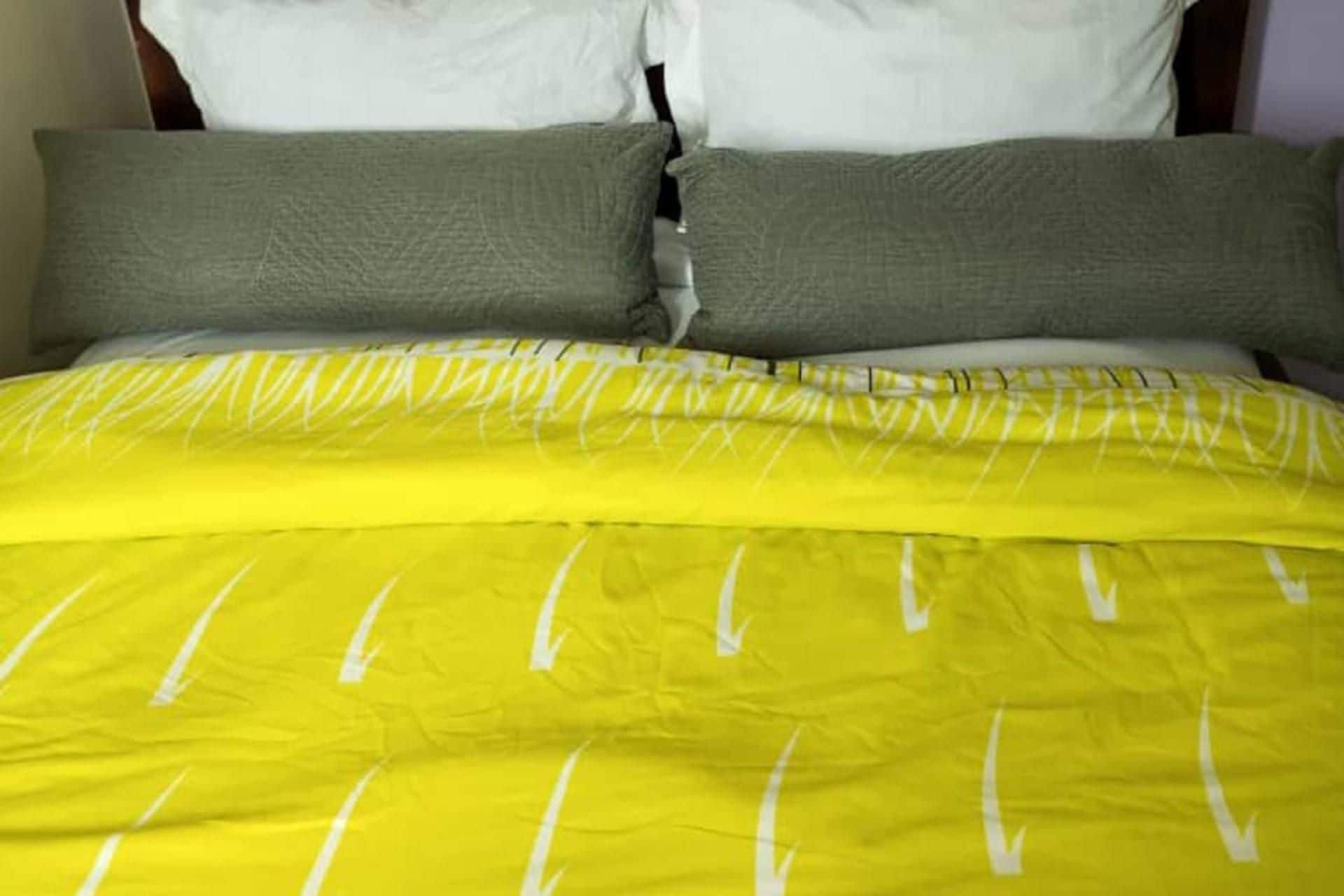 Un lit avec une couvre-lit jaune et deux oreillers.