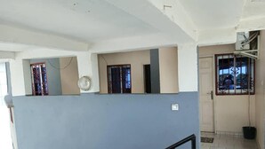 Un pasillo con pared azul, puerta blanca y ventana con celosías decorativas.