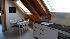 Eine Küche mit Oberlicht, weißen Schränken und einem Essbereich mit Tisch und Stühlen.