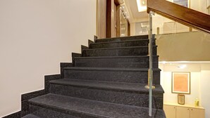 Un escalier avec des marches en marbre foncé et une rampe en bois.