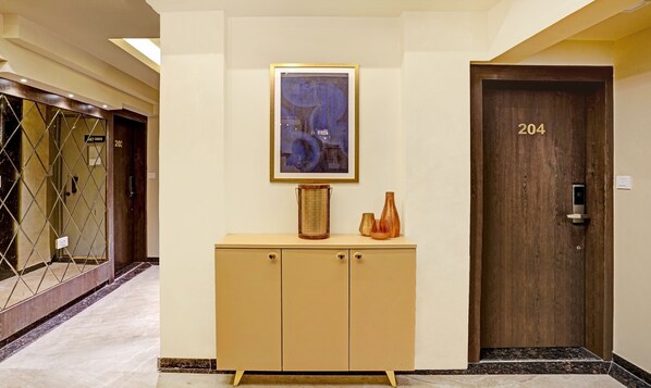 A hallway with a wooden door labeled 204, a beige cabinet with decorative items, and a framed artwork on the wall. - Treebo Premium Golden Bliss Trimurti Nagar Square (Nagpur)