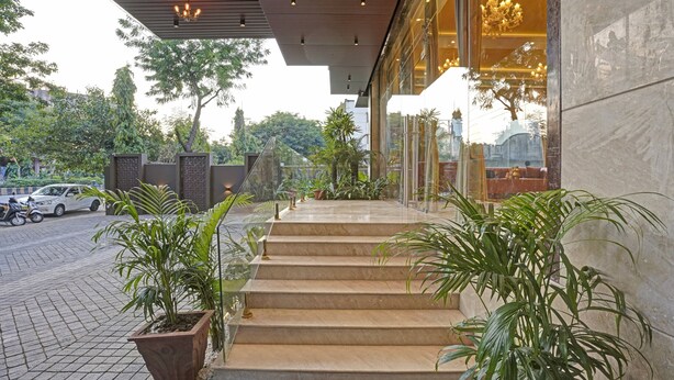 Une entrée moderne avec un escalier en marbre, des plantes en pot et une voiture garée.