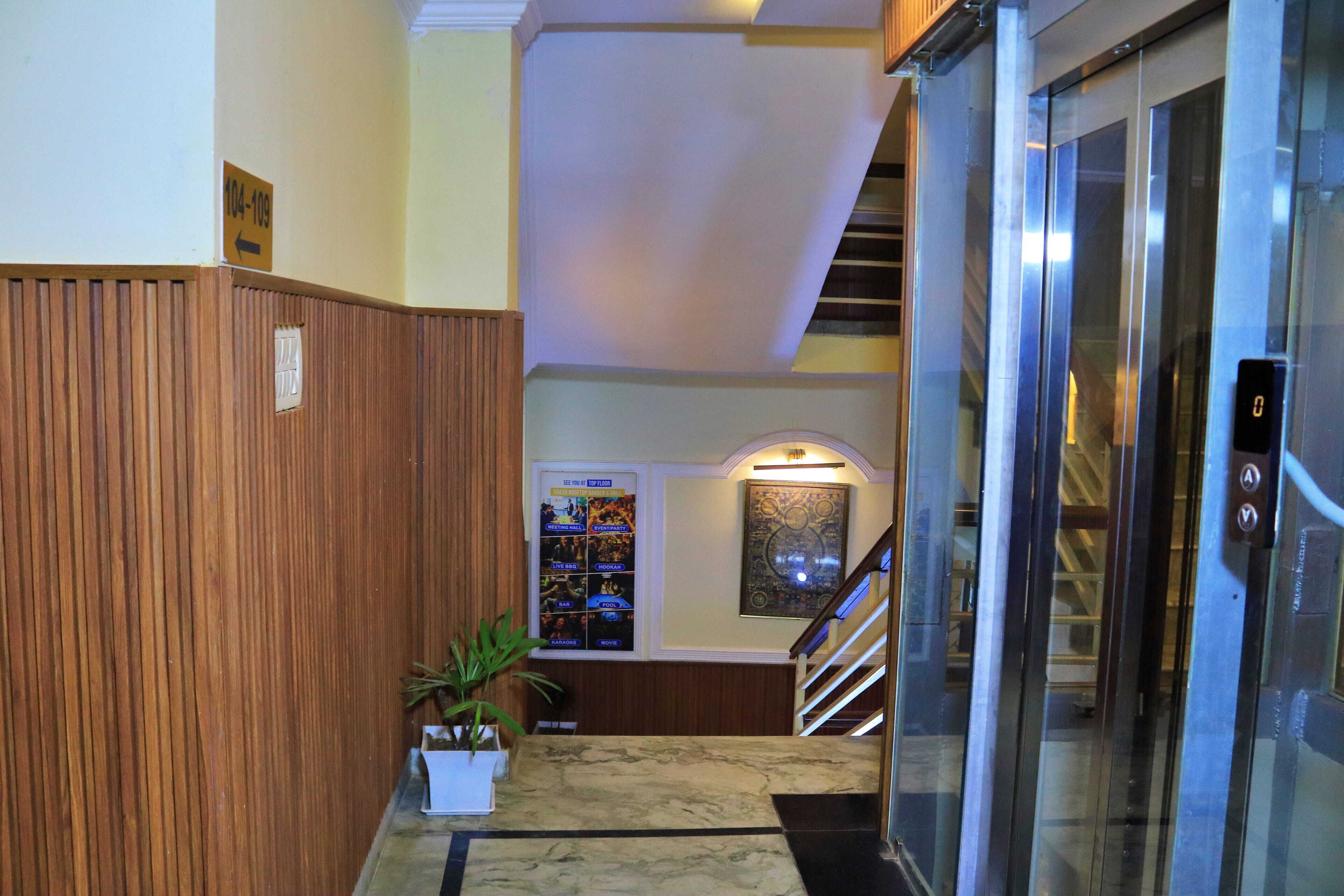 Un hall de hotel con un revestimiento de madera, una recepción de mármol, una escalera y un ascensor.