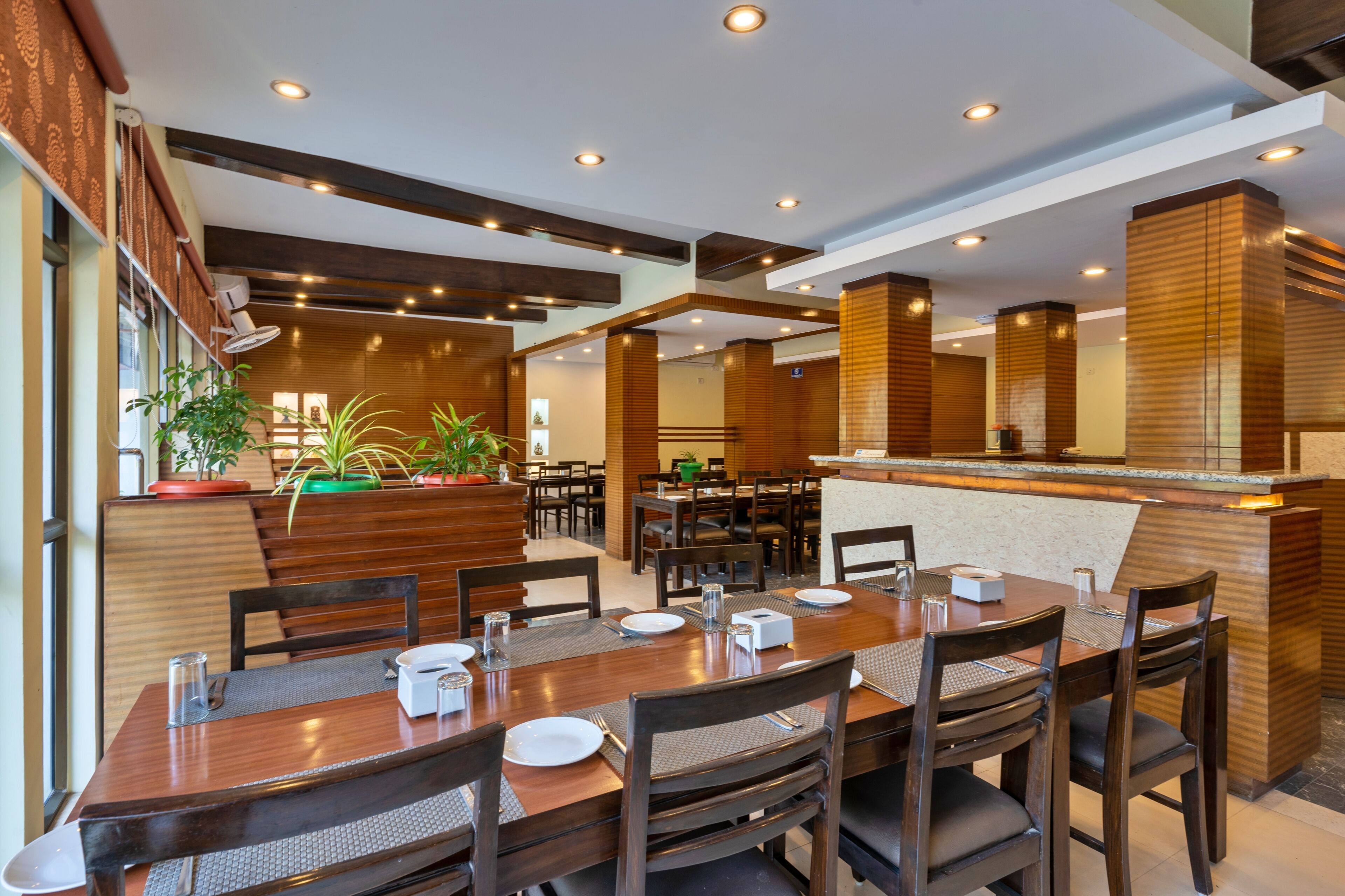 A restaurant with wooden furniture, a counter, and potted plants.