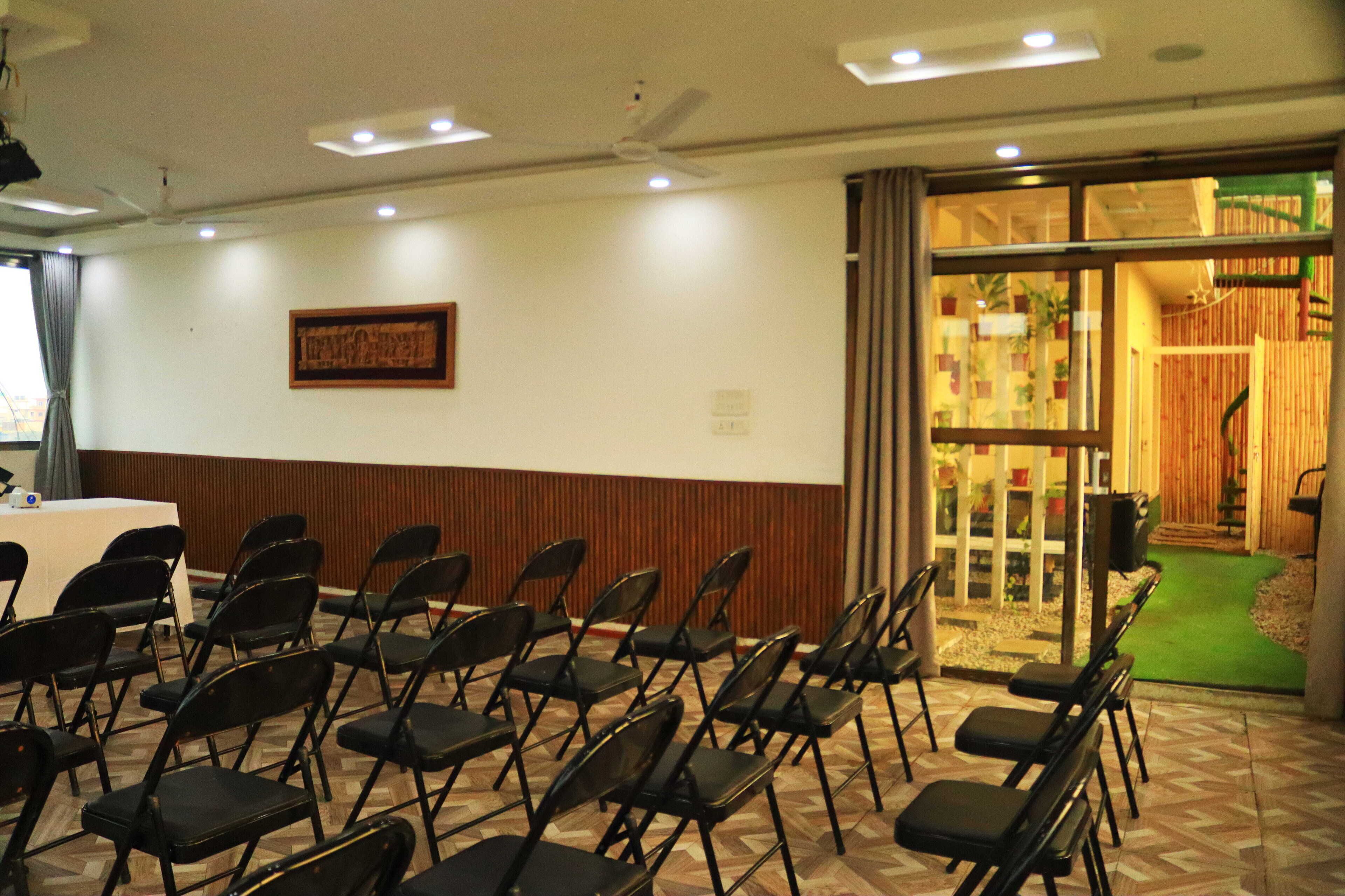 Un salón de conferencias con sillas plegables, una mesa y un ventilador de techo.