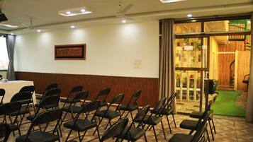 Un salón de conferencias con sillas plegables, una mesa y un ventilador de techo.