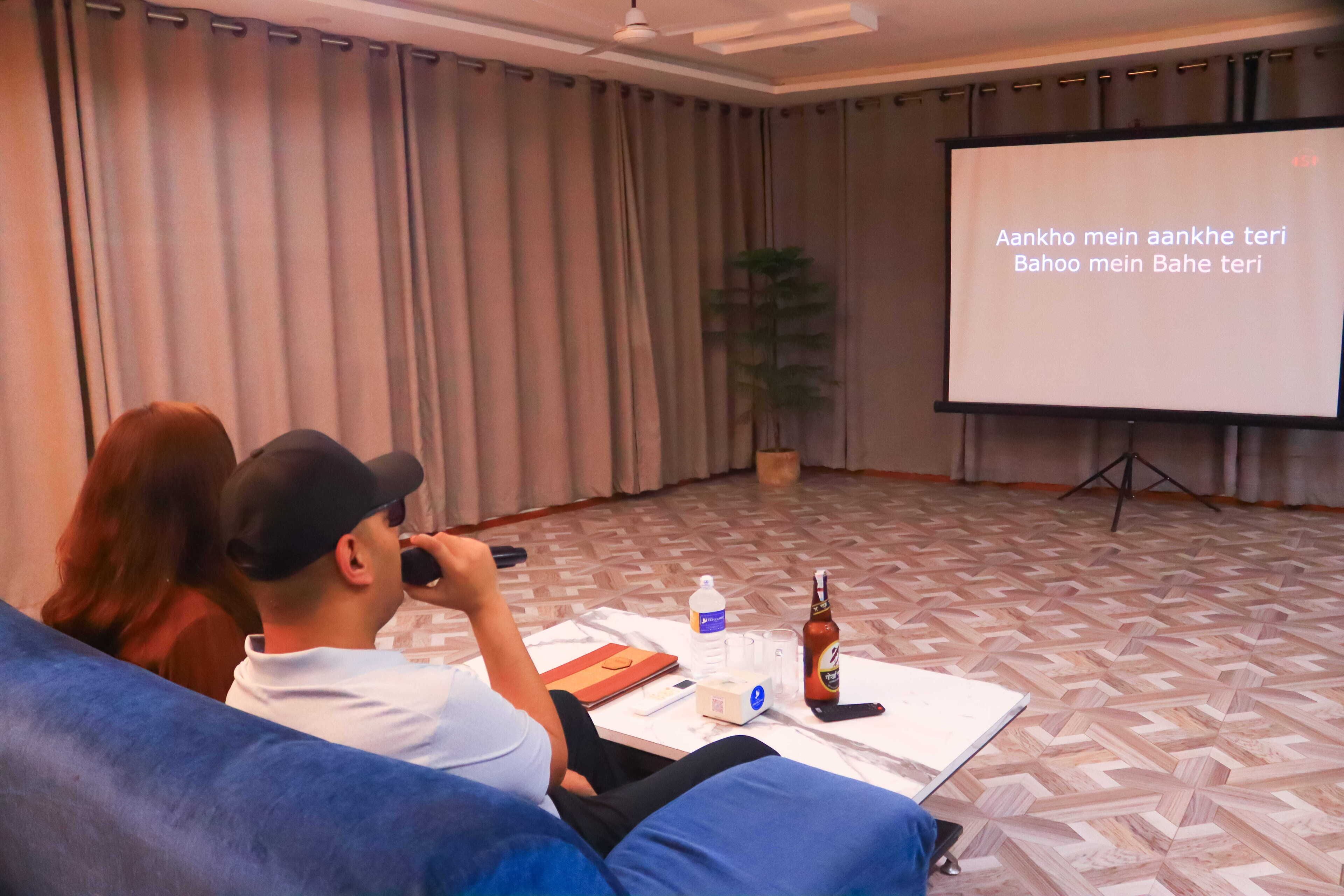 A conference room with a projector screen displaying text, a whiteboard, a table with a laptop, a bottle, and a water bottle.
