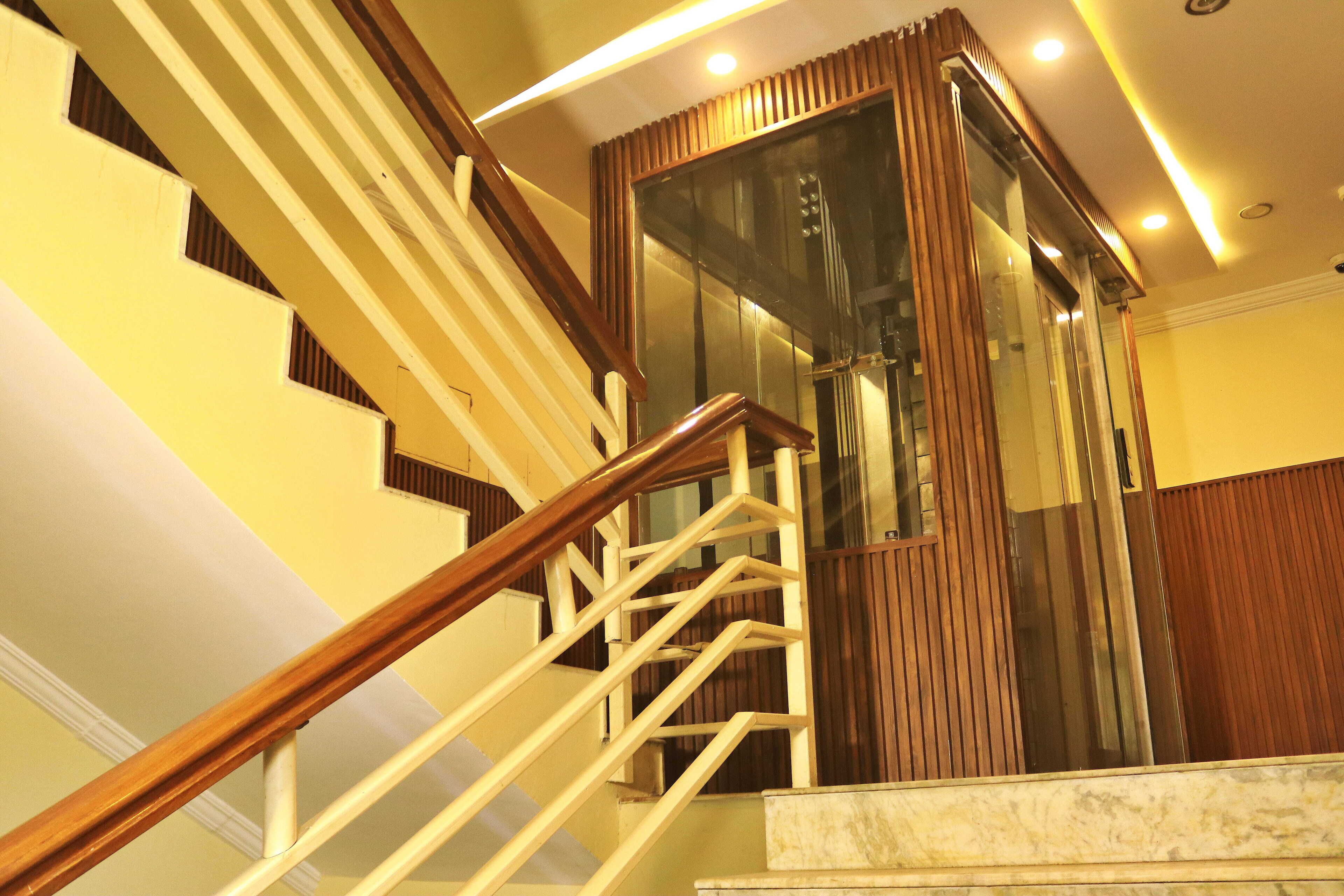 A staircase with wooden handrails and a glass elevator door.