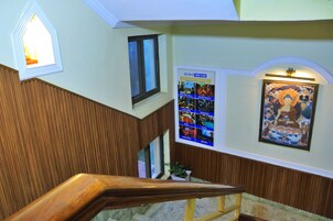 Una escalera con barandillas de madera, un tablón de anuncios con carteles de eventos y una obra de arte enmarcada en la pared.