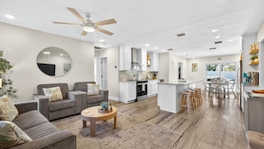 A modern living room with a sofa, coffee table, and a ceiling fan. - Steps to beach/Tiki Bar/Heated Pool/fun! (Indian Rocks Beach)