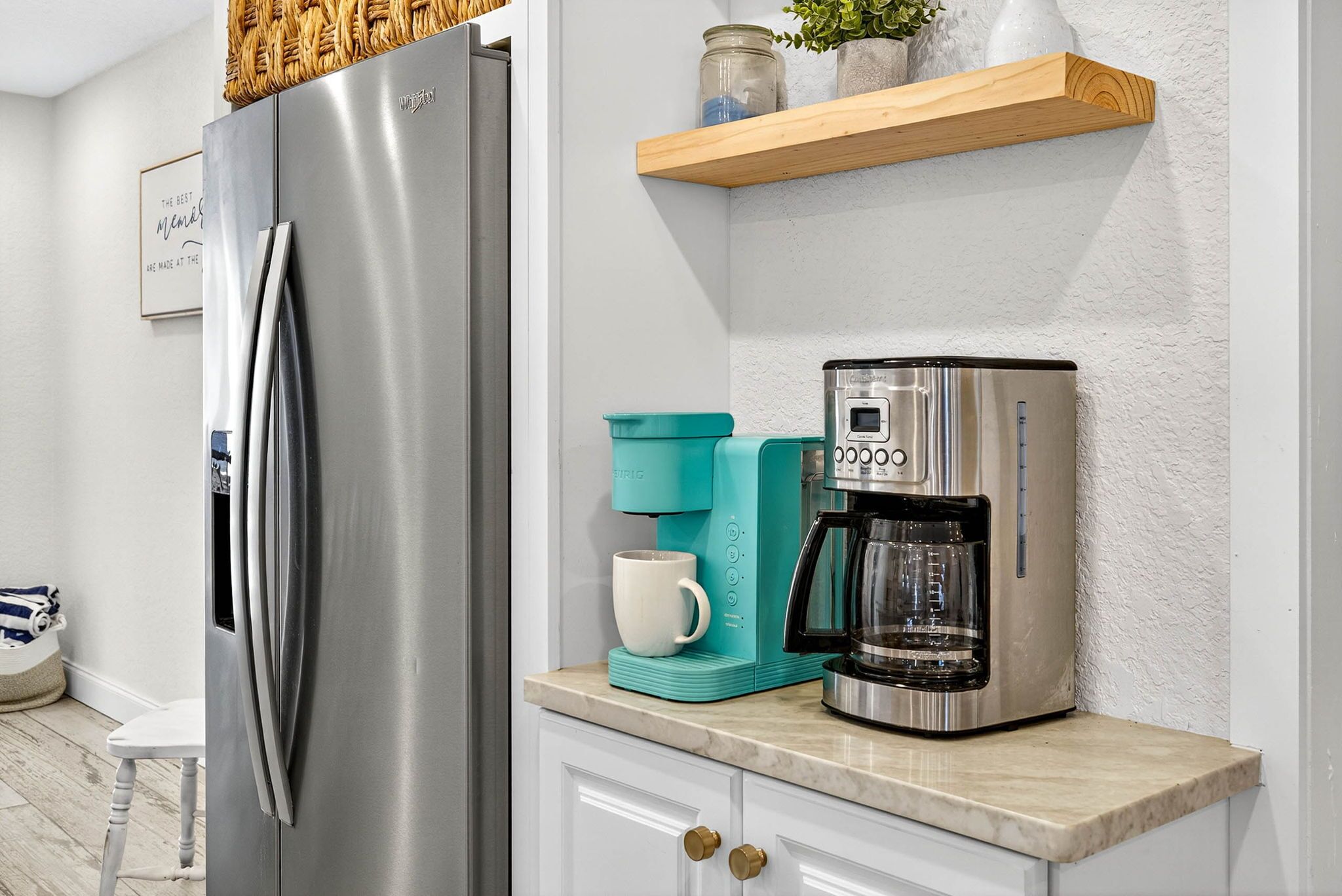 Une cuisine équipée d’un réfrigérateur en acier inoxydable, d’une machine à café et d’une tasse blanche posée sur le plan de travail.