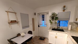 Una cocina compacta con armarios blancos, un lavamanos y un reloj en la pared.