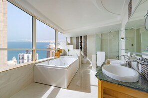 A modern bathroom with a large bathtub, a separate shower area, and a vanity with a sink. - Dusit Hotel & Suites Doha (Doha)