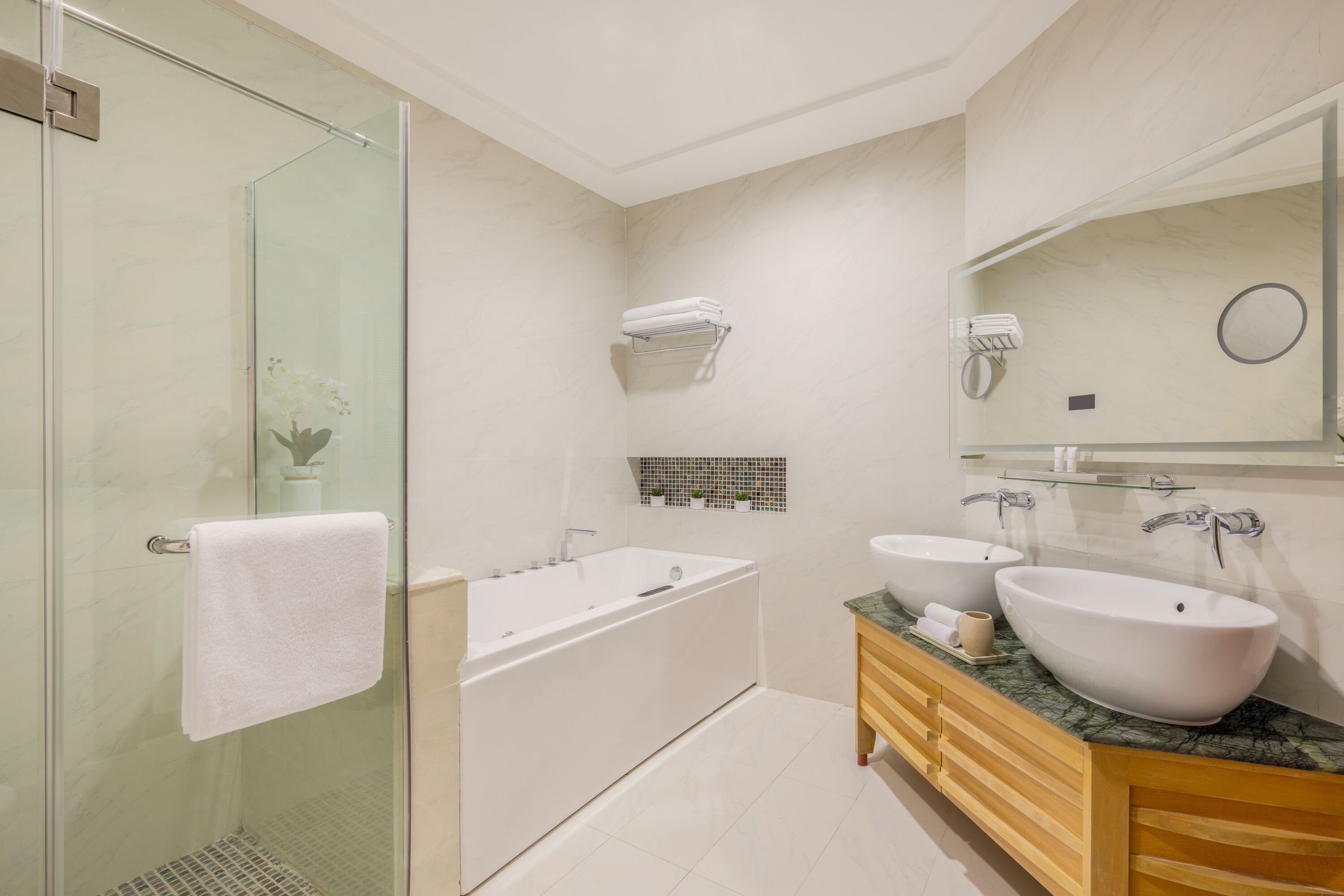 A modern bathroom with a glass shower enclosure, a freestanding bathtub, and a vanity with two sinks.