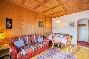A wooden-paneled room with a sofa, a table with chairs, and framed artwork on the walls.