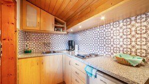 Una cocina con armarios de madera, un salpicadero estampado, una cafetera y una cesta en la encimera.