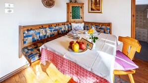 Una habitación acogedora con un banco de madera, una mesa con mantel blanco, una silla de madera y una lámpara amarilla.