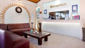 Zona de recepción con mostrador, un reloj en la pared, un sofá y una mesa de centro.