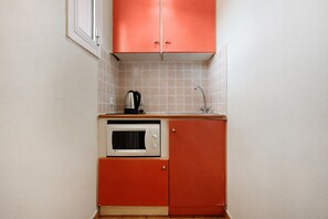 A compact kitchen with a microwave, kettle, and sink.