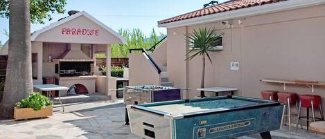 An outdoor pool area with a pool table, a barbecue area, and a building labeled 'PARADISE'.