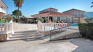 Une maison à deux étages dotée d’un balcon, d’une piscine et d’un escalier en pierre menant à l’entrée.