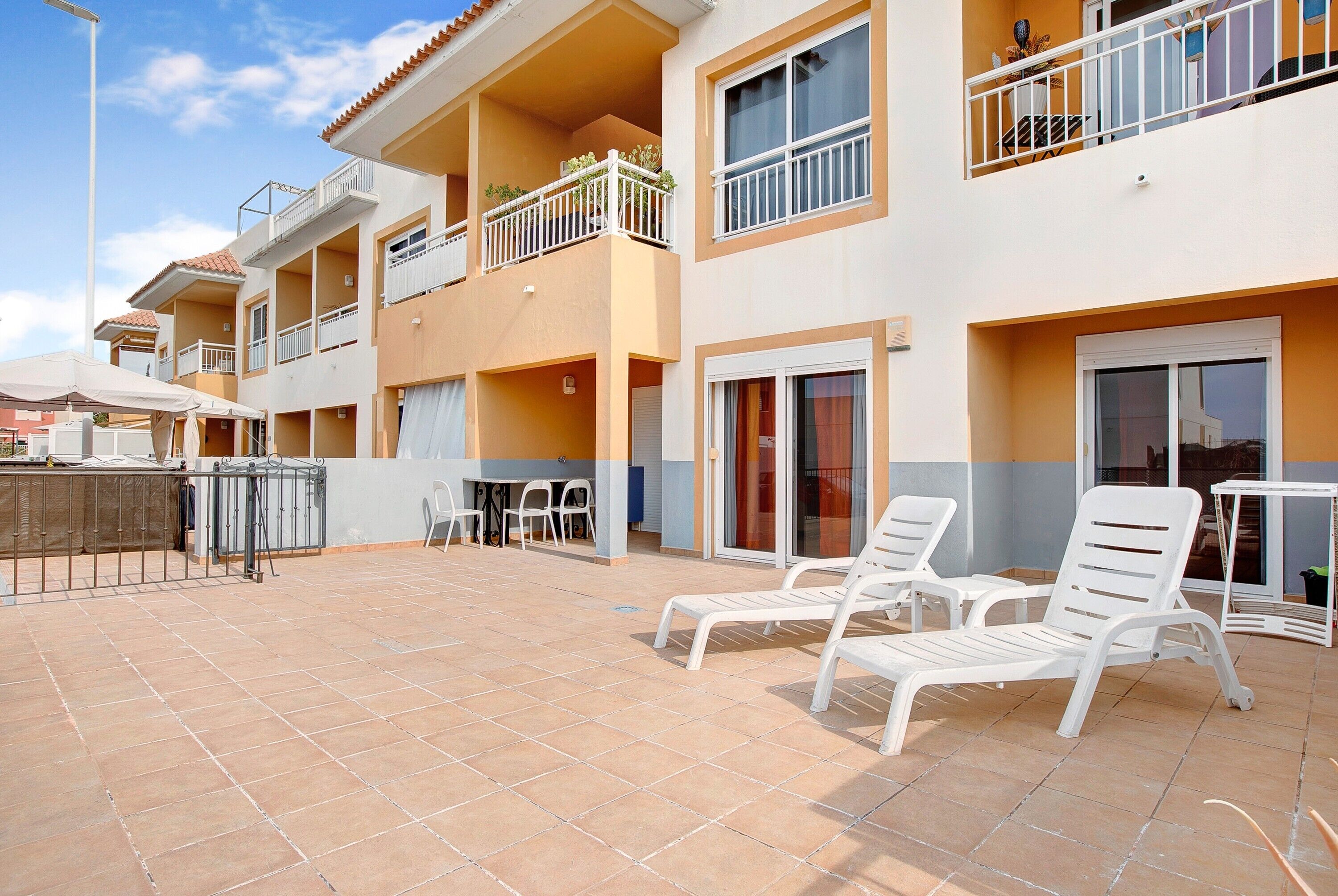 A multi-story residential building with balconies, outdoor seating, and a tiled patio area.