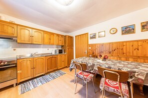 Une cuisine avec des meubles de rangement en bois, un four à micro-ondes et une table à manger avec des chaises.