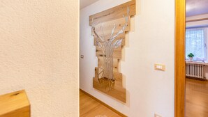 A hallway with a wooden wall art piece, a light switch, and a radiator. - Holiday Apartment "Ciasa Tach" with Mountain View, Balcony & Wi-Fi (Pozza di Fassa)