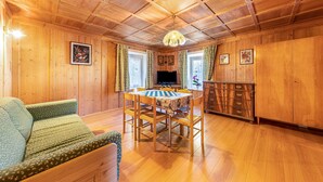 A wooden interior with a dining table, chairs, a sofa, and a television. - Holiday Apartment "Ciasa Tach" with Mountain View, Balcony & Wi-Fi (Pozza di Fassa)