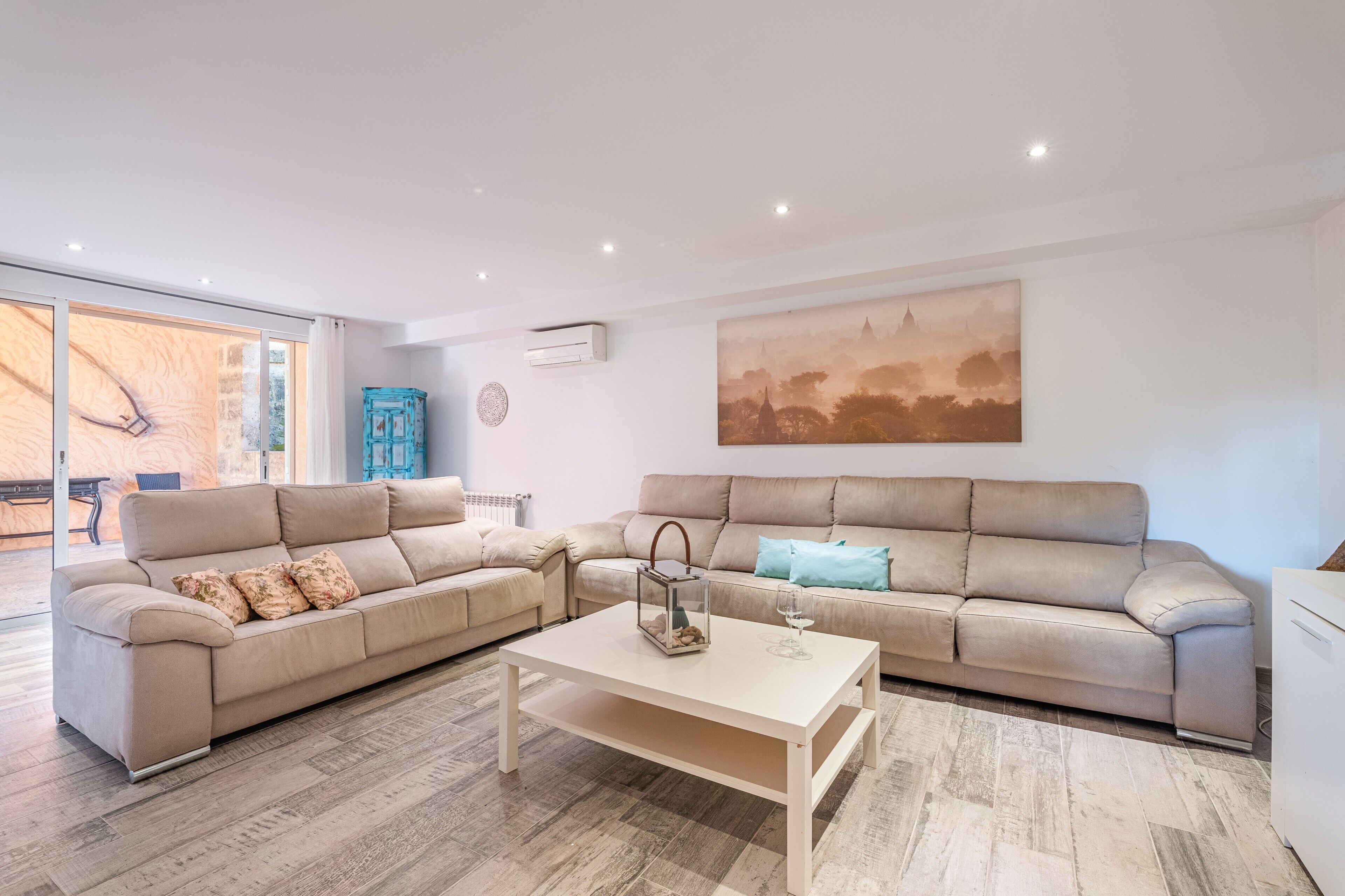 A modern living room with a beige sofa, a white coffee table, and a large painting on the wall.