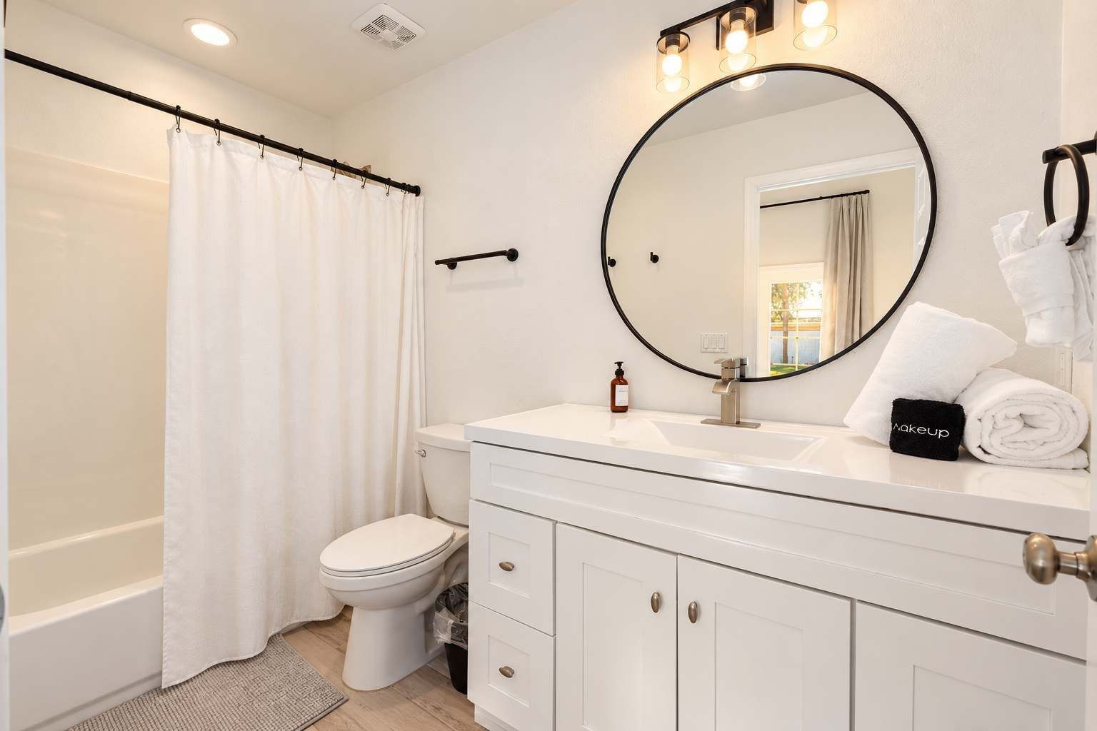 A bathroom with a shower curtain, toilet, sink with a mirror, and towels.