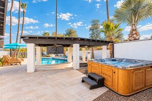 Un espace piscine comprenant un jacuzzi, des chaises longues et une pergola.