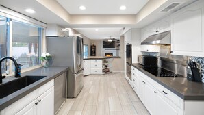 Een moderne keuken met witte kasten, roestvrijstalen apparatuur en een zwart aanrecht.