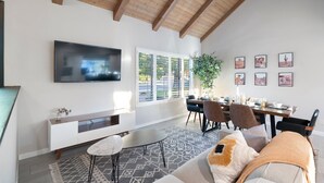 Een moderne woonkamer met een televisie, eettafel en comfortabele zithoek.