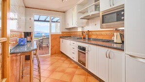 Une cuisine avec des meubles blancs, un four à micro-ondes et une vue sur l’extérieur.