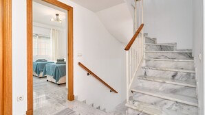 Un escalier en marbre avec des rampes en bois, un cadre de porte en bois et une vue sur une pièce où se trouvent un lit et une table.