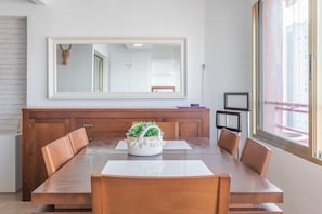 Un comedor con una mesa grande, sillas, un espejo y un ventanal.