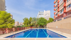 Una piscina con ringhiera rossa, circondata da alberi ed edifici.