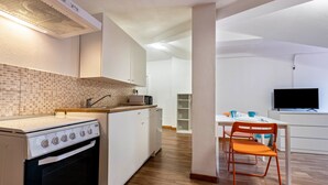 Una cocina moderna con armarios blancos, una estufa y un comedor con mesa y sillas.