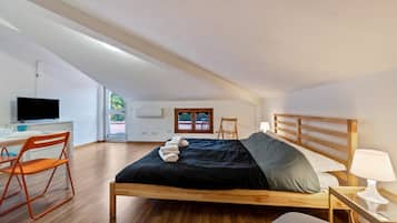 Une chambre à coucher avec un lit en bois, un bureau avec un ordinateur et une chaise.